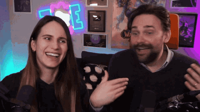 a man and a woman are talking in front of a neon sign that says ' e '