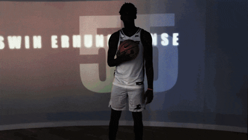 a man holding a basketball in front of a sign that says swim ernhouse 5