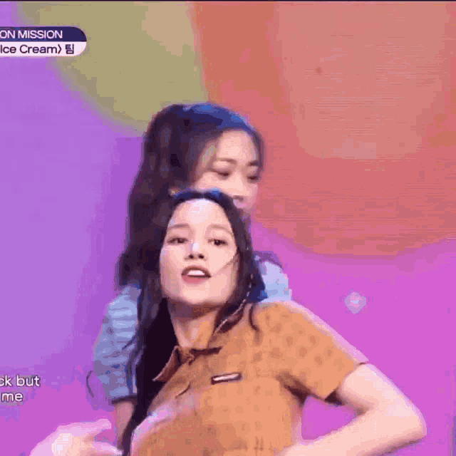 two women are dancing on a stage and one of them is waving her hand .