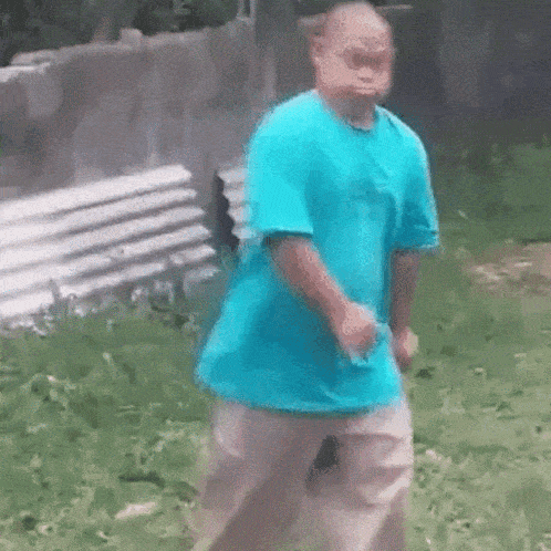 a man in a blue shirt is dancing in front of a bench .