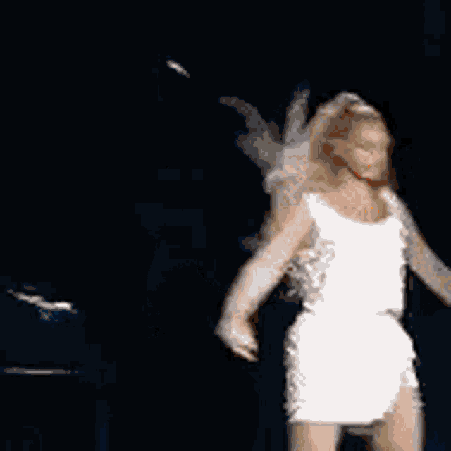 a woman in a white dress is dancing in the dark .