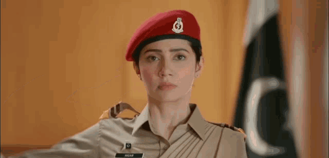 a woman in a military uniform is wearing a red beret and saluting .