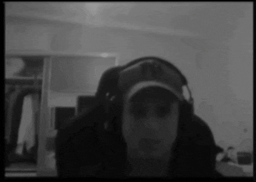 a man wearing headphones and a hat looks at the camera