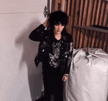 a woman in a black jacket and black pants is standing in front of a white door