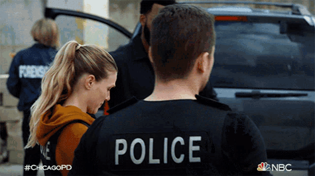 a man wearing a black police uniform stands next to a woman