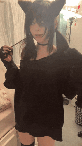 a woman wearing cat ears and a black sweater is holding a stick