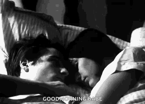 a black and white photo of a man and woman laying in bed with the words `` good morning babe '' written on the bottom .
