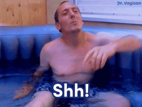a shirtless man is sitting in a bathtub with the words shh written on the bottom