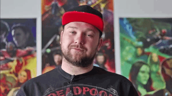 a man wearing a red hat and a black shirt with the word deadpool on it