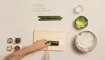 a person is cutting a cucumber on a cutting board next to bowls of food .