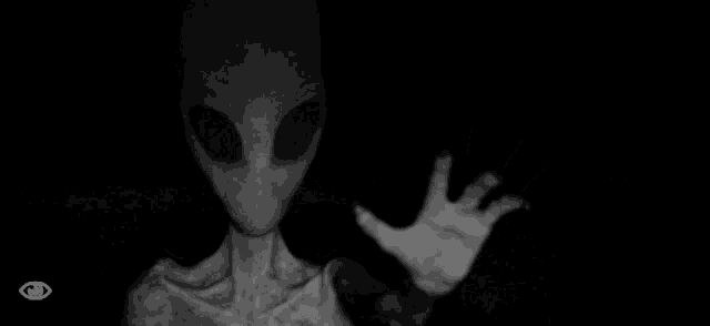 a black and white photo of an alien with its hand outstretched .
