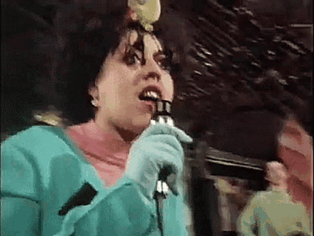 a woman singing into a microphone while wearing a blue jacket