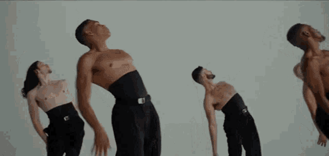 a group of men are standing next to each other in a room without shirts .