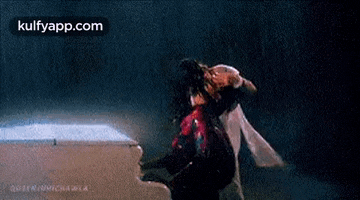 a man is holding a woman in his arms and kissing her in a dark room .