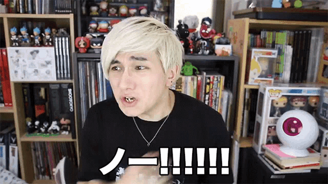 a man in a black shirt is standing in front of a bookshelf with toys on it and a sign that says !!!