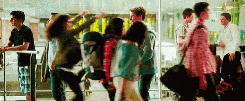 a group of people are walking through a glass door at an airport .