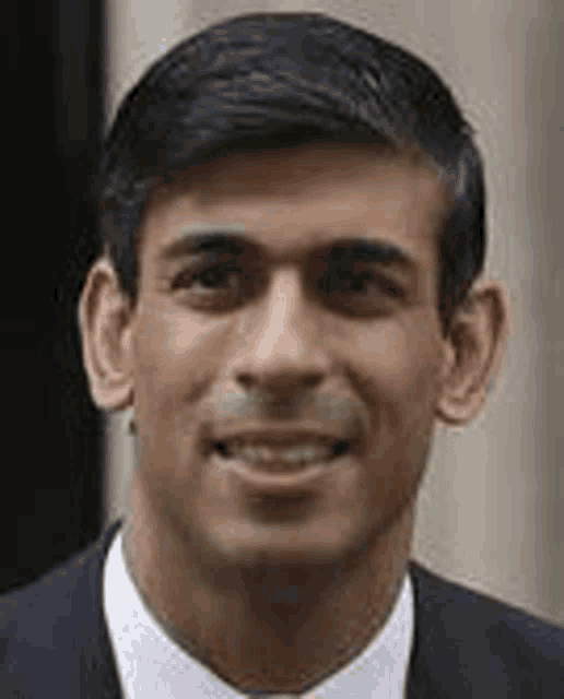 a close up of a man wearing a suit and tie smiling .
