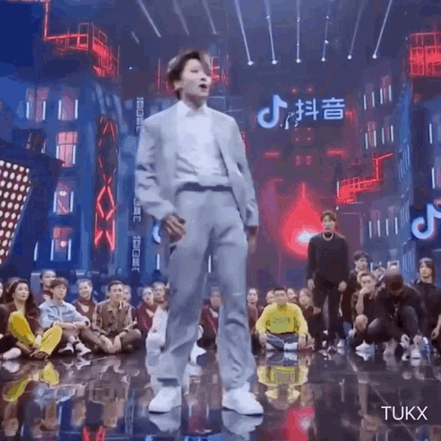 a man in a suit is standing on a stage in front of a crowd of people .