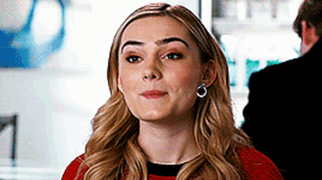 a close up of a woman wearing earrings and a red shirt .