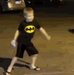 a young boy wearing a black batman shirt is dancing