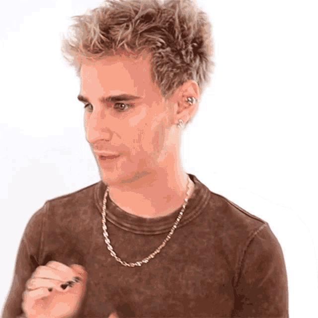 a man wearing a brown shirt and a gold chain