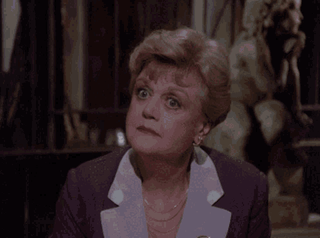 a woman in a purple suit looks surprised in front of a statue of a man