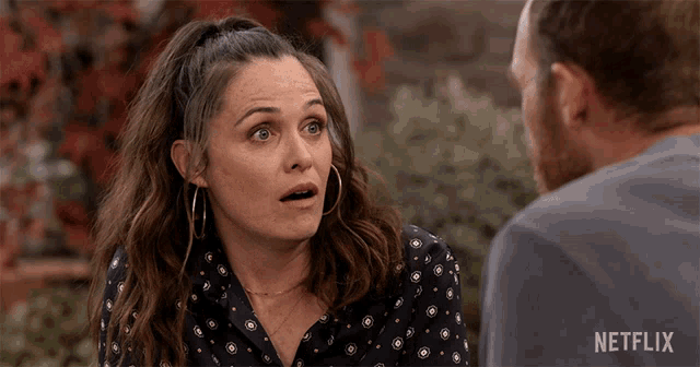 a woman with a surprised look on her face talks to a man with a netflix logo in the corner