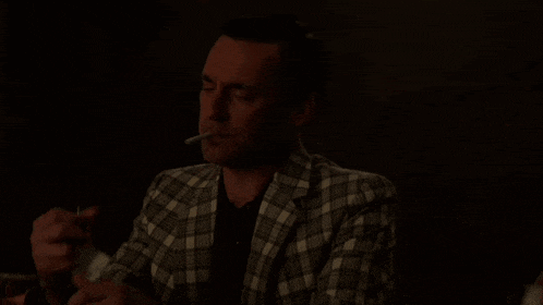 a man in a plaid suit is smoking a cigarette