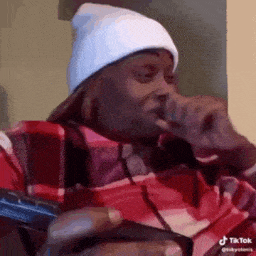 a man wearing a white beanie and a plaid shirt is holding a gun .