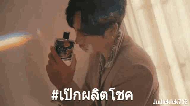 a man in a suit is smelling a bottle of perfume with the hashtag #