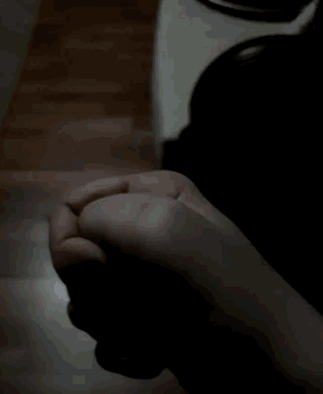 a person 's hand is holding a black object in the dark