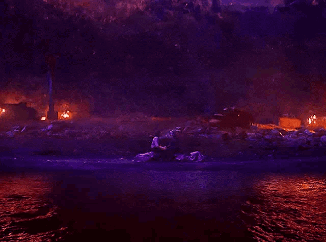 a group of people are standing in a body of water surrounded by fire