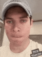 a man wearing a hat and a white t-shirt is making a funny face .