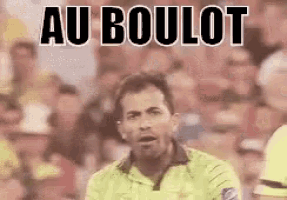 a man in a yellow shirt is standing in front of a crowd with the words `` au boulot '' written on it .