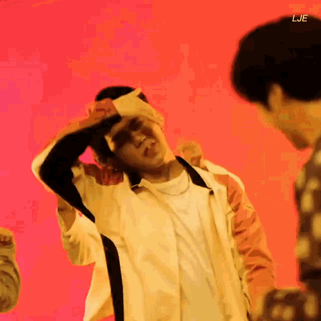 a man is covering his eyes with a piece of paper while dancing in front of a red background .