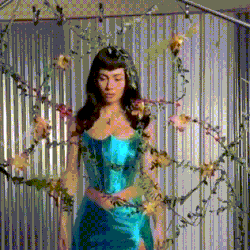 a woman in a blue dress is surrounded by vines