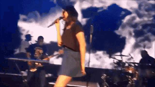 a woman singing into a microphone on stage with a man playing a keyboard in the background