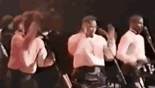 a group of people are singing into microphones on stage .