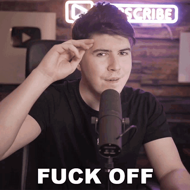 a man sitting in front of a microphone with the words " fuck off " written below him