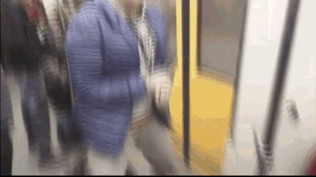 a blurry picture of a woman in a blue jacket walking on a train