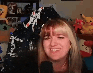 a woman is smiling in front of a microphone in a room filled with toys .