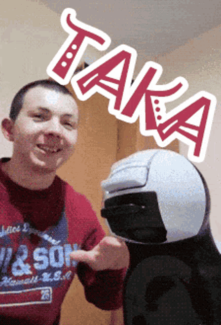 a man wearing a red shirt with the word son on it points at a helmet