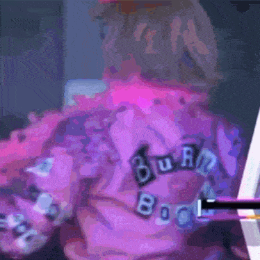 a blurry picture of a person wearing a purple shirt that says burn book