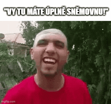 a man in a red shirt is making a funny face while standing in front of trees .