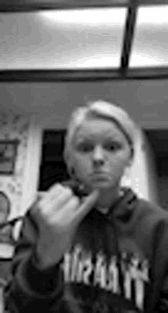 a girl in a hoodie is giving the middle finger .