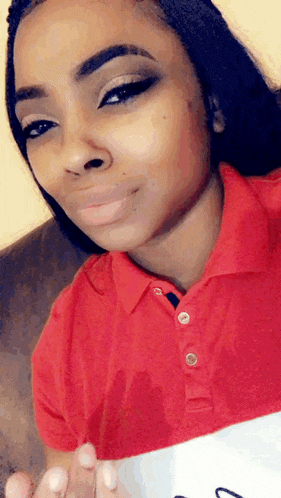 a woman is wearing a red polo shirt and smiling
