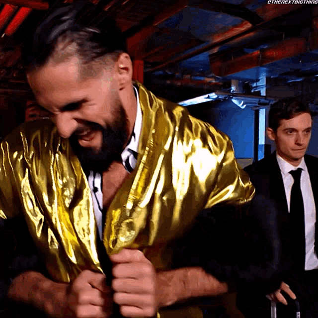 a man in a gold robe is standing next to another man in a suit and tie