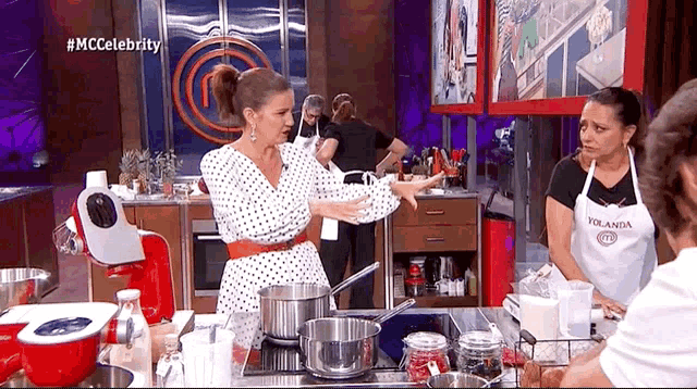 a woman in a polka dot dress is cooking on a stove in a kitchen