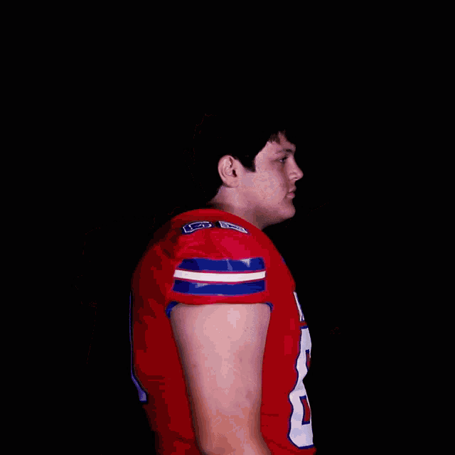 a football player wearing a red nelson jersey with his arms crossed