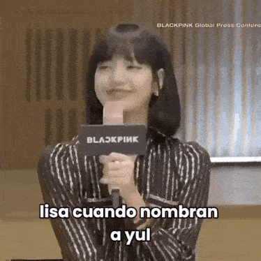 a woman is holding a microphone in front of a sign that says blackpink on it .